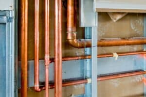 Exposed copper pipes and metal framing in a partially constructed wall highlight the intricate work involved in a home re-pipe. Snellville residents can appreciate the blend of form and function during such transformations.